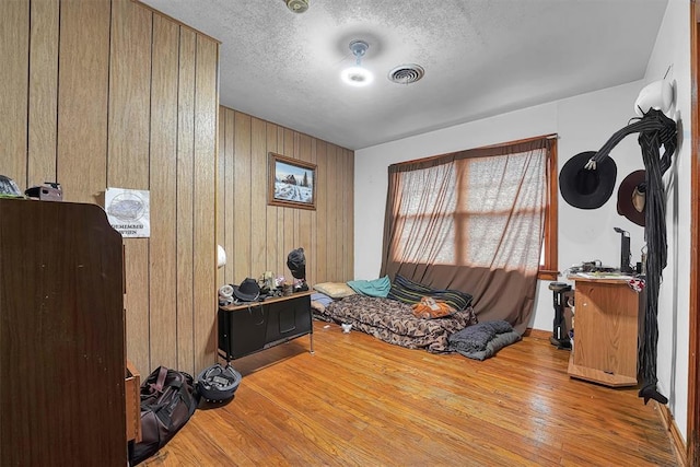 sitting room featuring a textured ceiling, wood finished floors, and wooden walls