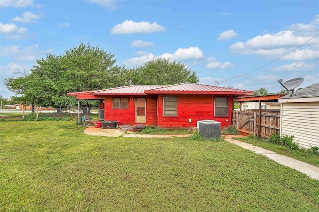 rear view of house featuring fence, central AC unit, a gate, metal roof, and a yard
