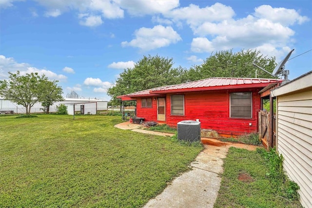 back of property featuring metal roof, central air condition unit, a yard, and fence