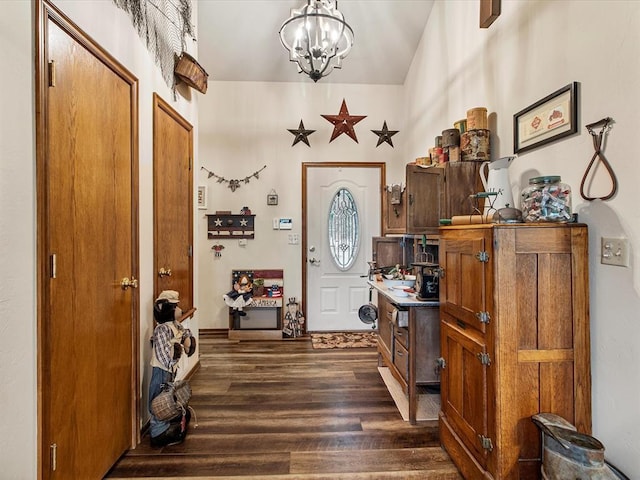 foyer entrance featuring dark wood-style flooring, a chandelier, and lofted ceiling