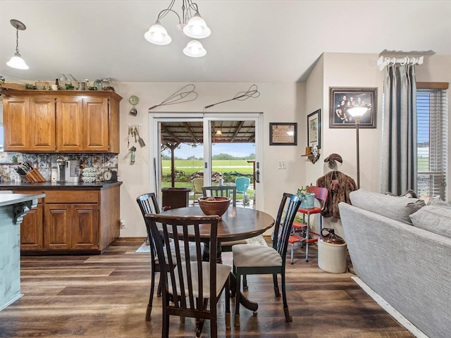dining space with baseboards, a notable chandelier, and dark wood-type flooring