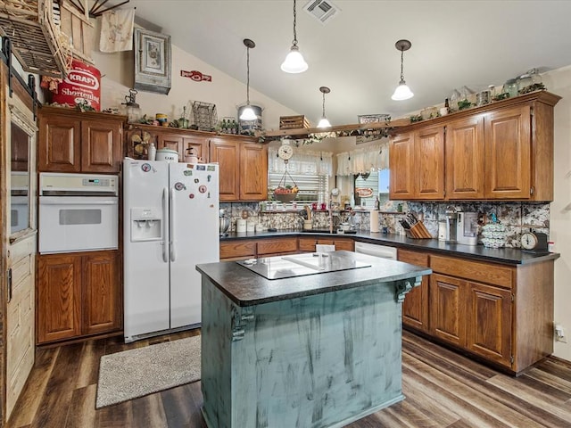 kitchen featuring dark countertops, white appliances, dark wood finished floors, lofted ceiling, and visible vents