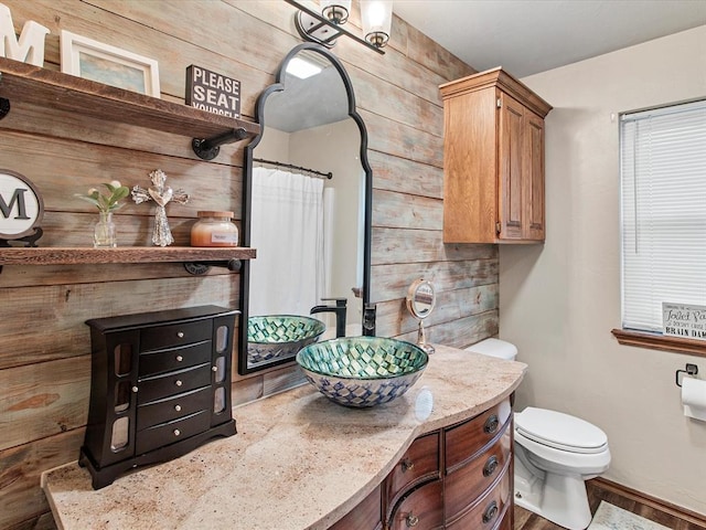 bathroom with wooden walls, toilet, and vanity