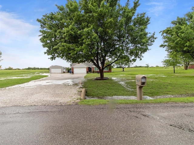 view of property hidden behind natural elements featuring gravel driveway and a front lawn