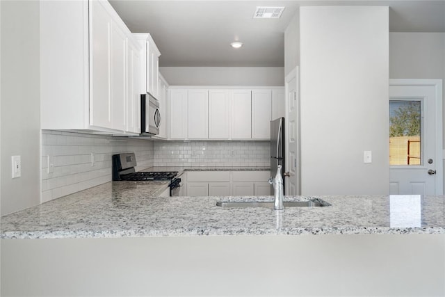 9324 NW 126th St, Yukon, OK 73099 - kitchen featuring visible vents, decorative backsplash, light stone countertops, a sink, and appliances with stainless steel finishes