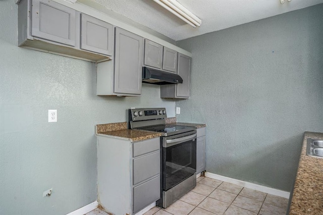 1824 David Ter, Oklahoma City, OK 73141 - kitchen with gray cabinets, stainless steel electric range, under cabinet range hood, light tile patterned floors, and baseboards