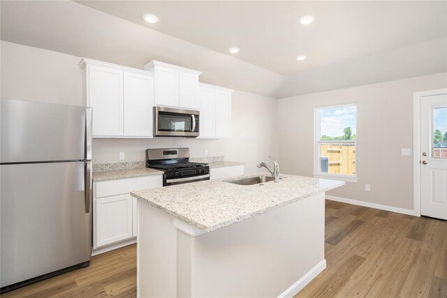 kitchen featuring a kitchen island with sink, light wood-type flooring, a sink, white cabinets, and stainless steel appliances