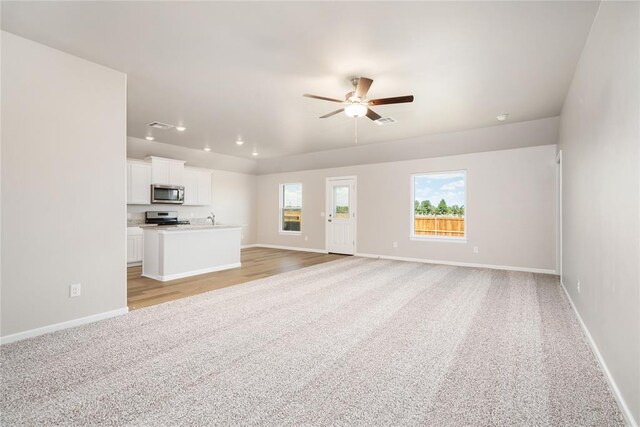 unfurnished living room featuring baseboards, light carpet, a ceiling fan, and recessed lighting