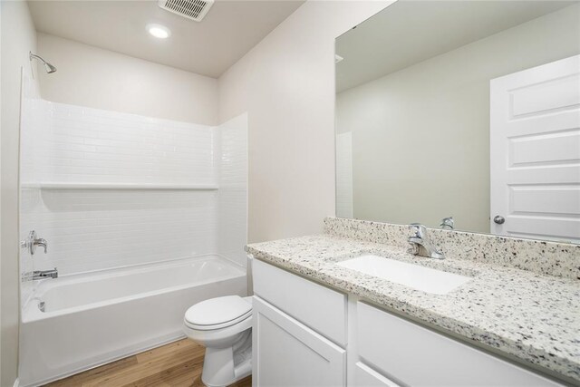 bathroom with vanity, toilet, tub / shower combination, wood finished floors, and visible vents