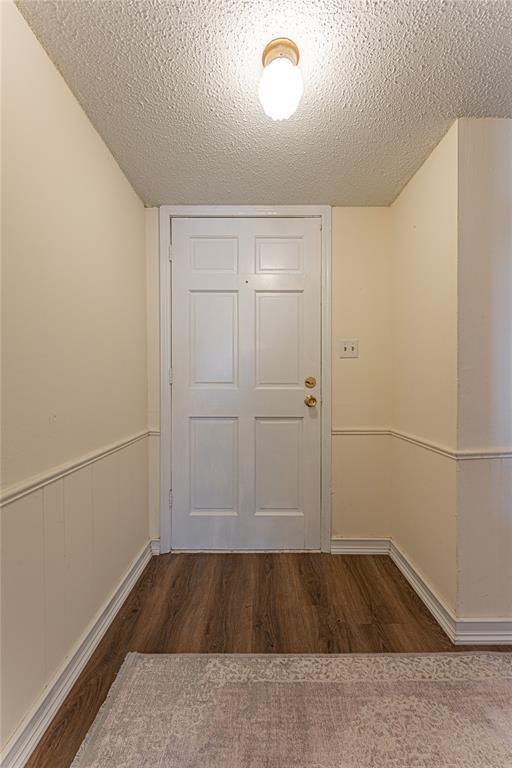 doorway to outside featuring a textured ceiling and wood finished floors