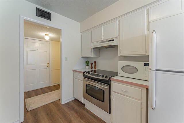 kitchen featuring white appliances, a textured ceiling, dark wood finished floors, under cabinet range hood, and visible vents