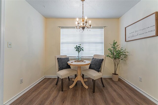 dining room featuring a textured ceiling, baseboards, wood finished floors, and a chandelier
