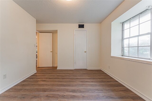 unfurnished bedroom with visible vents, baseboards, a textured ceiling, and wood finished floors