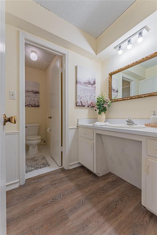 bathroom with vanity, a textured ceiling, wood finished floors, and toilet