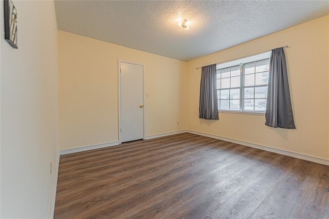 unfurnished room featuring baseboards, a textured ceiling, and wood finished floors