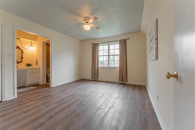 unfurnished bedroom featuring a textured ceiling, baseboards, a ceiling fan, and wood finished floors