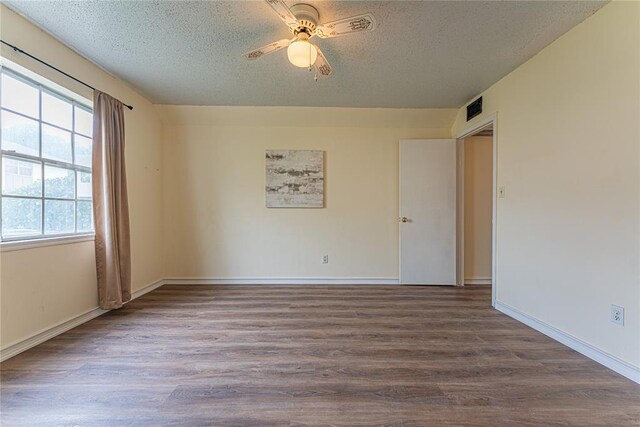 spare room featuring a textured ceiling, visible vents, and wood finished floors