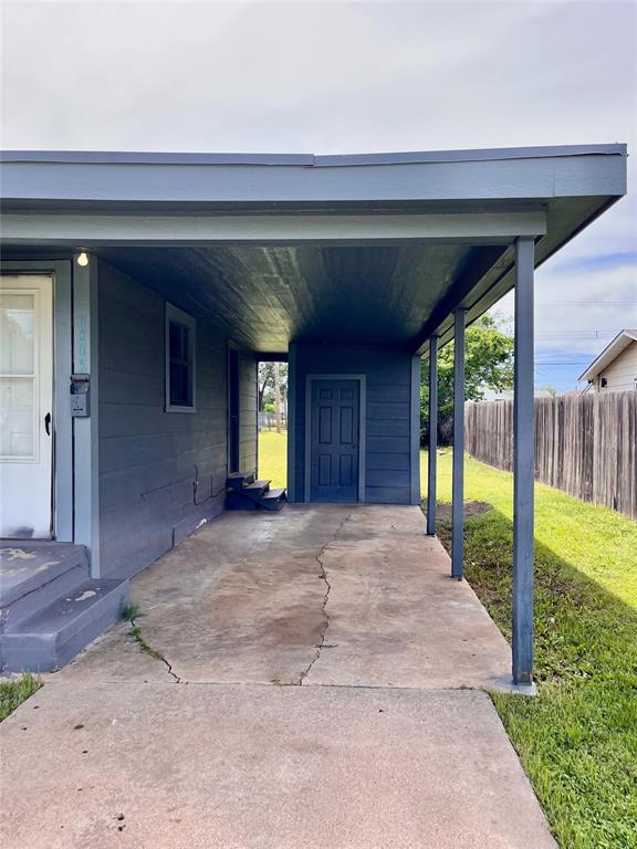 view of parking / parking lot featuring fence and an attached carport