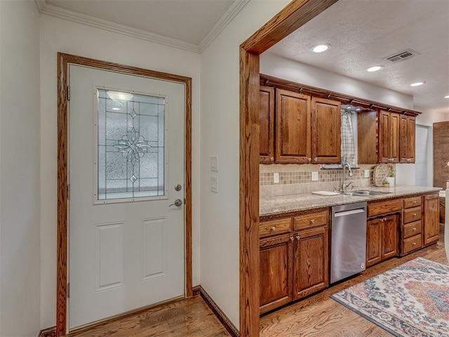 kitchen with stainless steel dishwasher, light wood-type flooring, brown cabinets, tasteful backsplash, and a sink