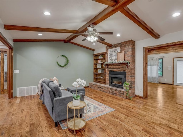 living room featuring ceiling fan, lofted ceiling with beams, baseboards, wood finished floors, and visible vents