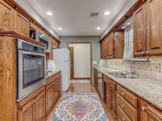 kitchen featuring visible vents, a sink, appliances with stainless steel finishes, and brown cabinets