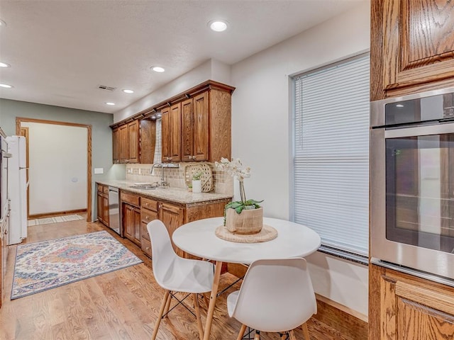 kitchen featuring a sink, light wood-style flooring, brown cabinets, and stainless steel appliances