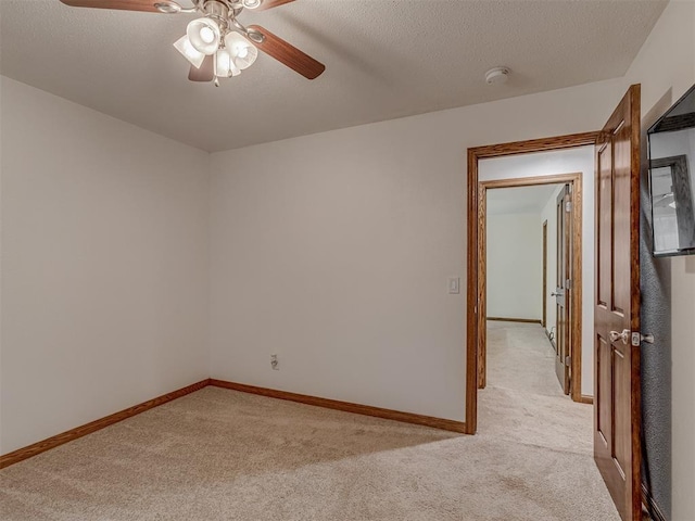 empty room featuring baseboards, a ceiling fan, a textured ceiling, and light carpet