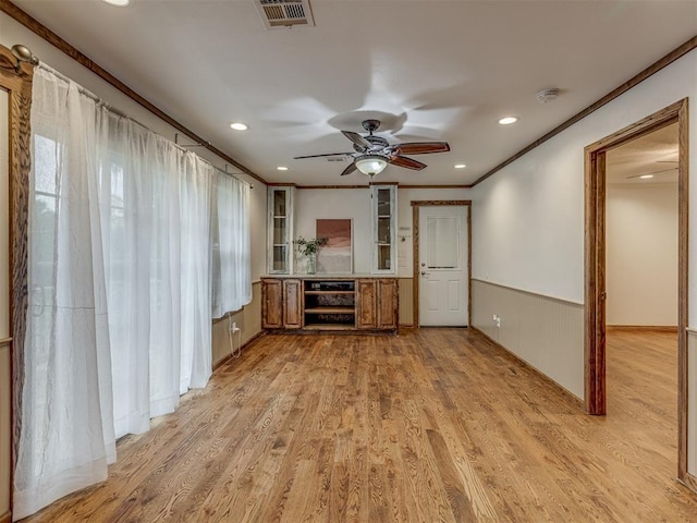unfurnished living room with visible vents, a ceiling fan, ornamental molding, and light wood-type flooring