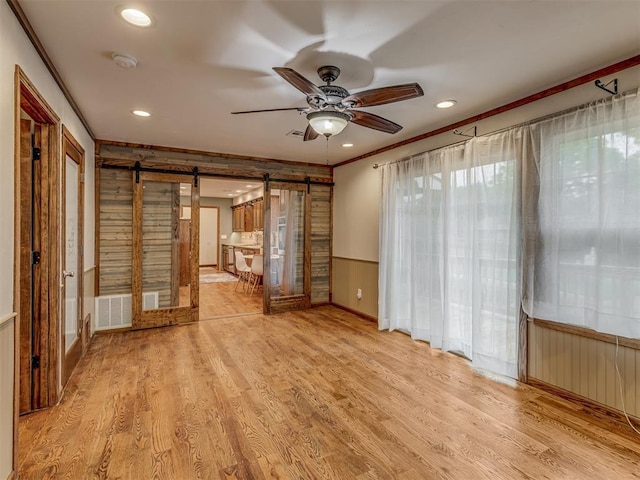 interior space featuring crown molding, a barn door, recessed lighting, light wood-type flooring, and visible vents