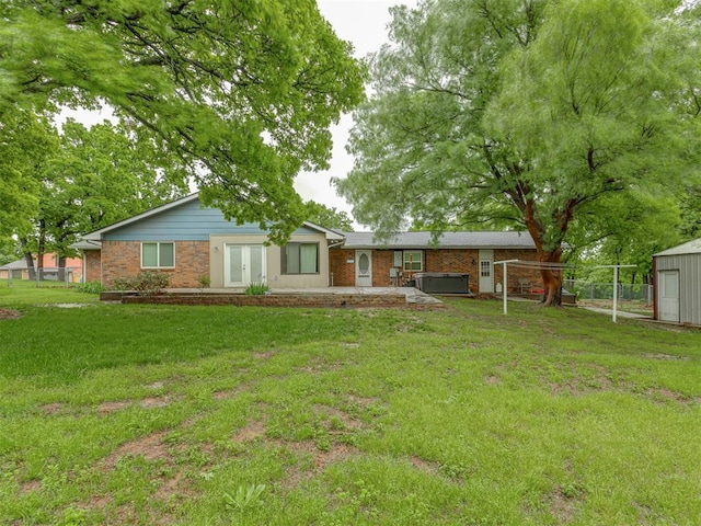 rear view of property featuring brick siding, french doors, fence, and a yard