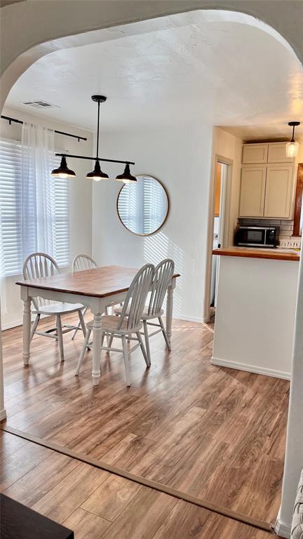 211 W Corbin Ave, Altus, OK 73521 - dining space featuring arched walkways, baseboards, visible vents, and light wood-style floors