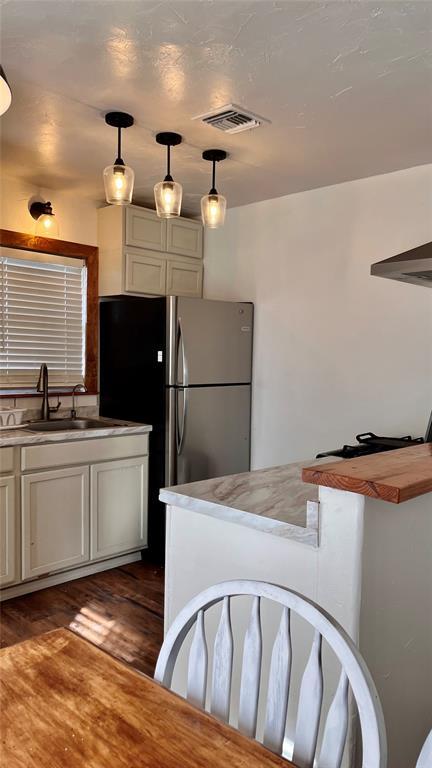 kitchen with hanging light fixtures, visible vents, dark wood-style floors, and a sink