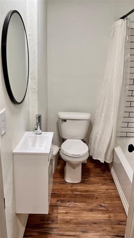 full bathroom with vanity, wood finished floors, toilet, baseboards, and shower / bathtub combination with curtain