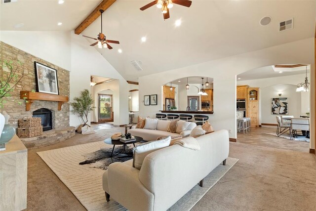 living area featuring light colored carpet, arched walkways, high vaulted ceiling, a ceiling fan, and visible vents