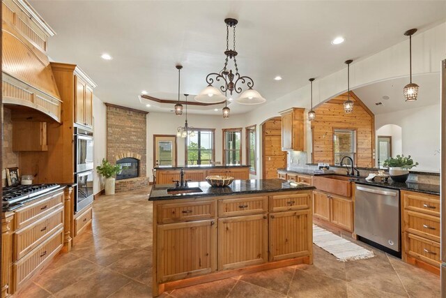 kitchen with a center island with sink, recessed lighting, arched walkways, a sink, and stainless steel appliances