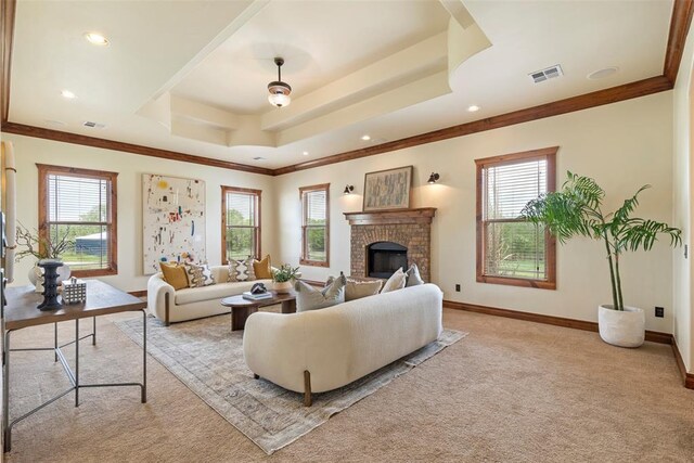 carpeted living area featuring crown molding, visible vents, a brick fireplace, baseboards, and a raised ceiling