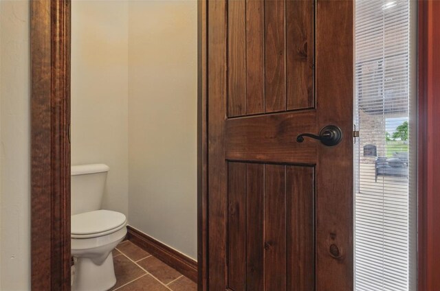 bathroom featuring toilet, baseboards, and tile patterned flooring
