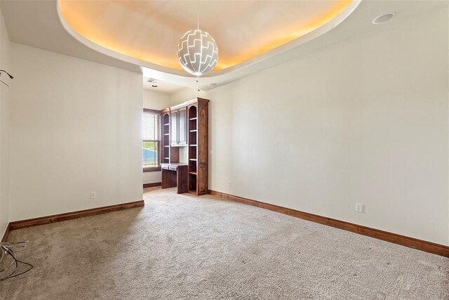 spare room featuring baseboards, light carpet, and a tray ceiling
