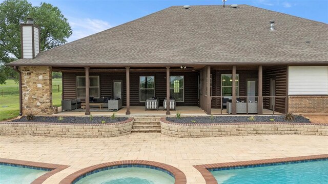 rear view of property featuring outdoor lounge area, a patio, an outdoor pool, roof with shingles, and a chimney