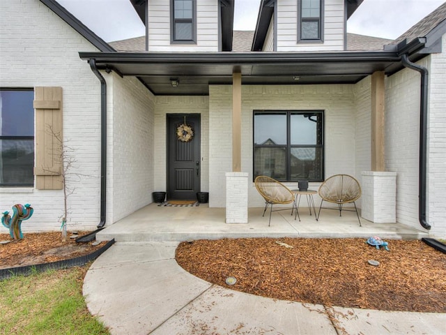18444 Posse Trl, Norman, OK 73071 - view of exterior entry with covered porch, brick siding, and a shingled roof
