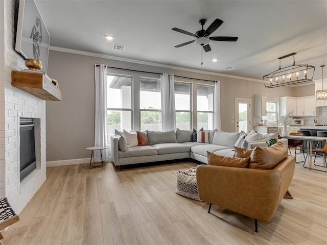 18444 Posse Trl, Norman, OK 73071 - living area with ceiling fan, a brick fireplace, light wood-type flooring, visible vents, and ornamental molding