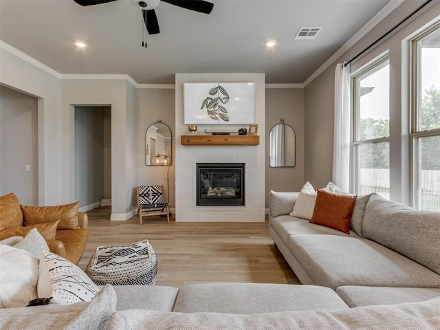 18444 Posse Trl, Norman, OK 73071 - living room featuring visible vents, a fireplace, baseboards, ornamental molding, and light wood-style flooring