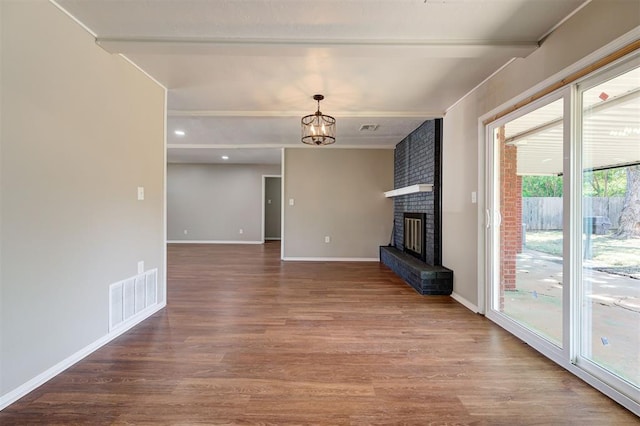 1508 Carlton Way, Oklahoma City, OK 73120 - unfurnished living room with a brick fireplace, baseboards, wood finished floors, beamed ceiling, and visible vents