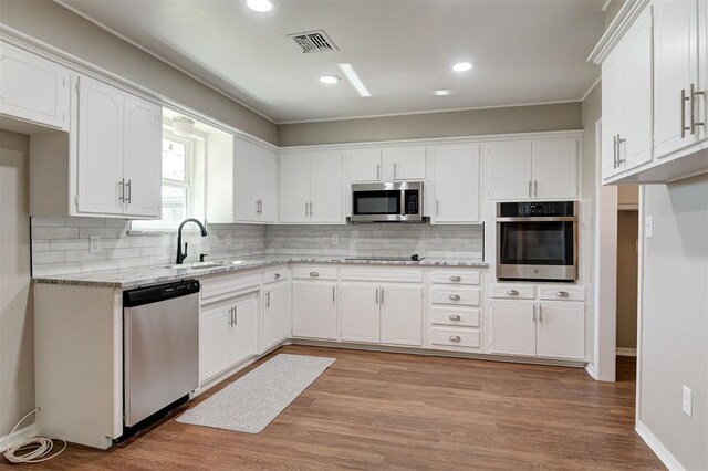 1508 Carlton Way, Oklahoma City, OK 73120 - kitchen with visible vents, decorative backsplash, white cabinets, a sink, and stainless steel appliances