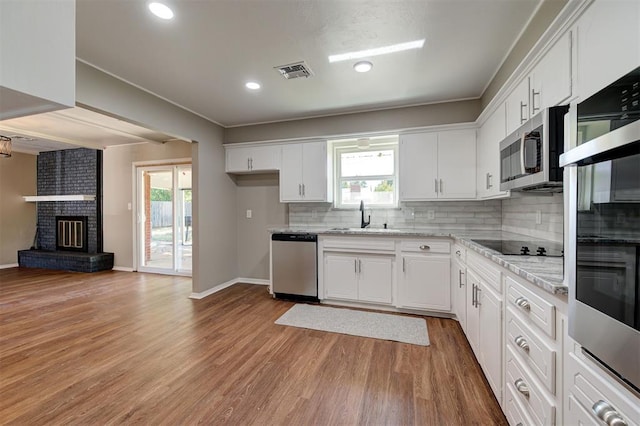 1508 Carlton Way, Oklahoma City, OK 73120 - kitchen with visible vents, white cabinetry, tasteful backsplash, a sink, and appliances with stainless steel finishes