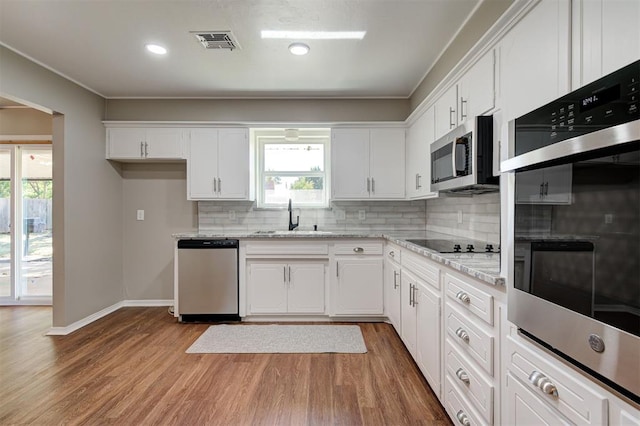 1508 Carlton Way, Oklahoma City, OK 73120 - kitchen featuring visible vents, decorative backsplash, white cabinets, a sink, and stainless steel appliances