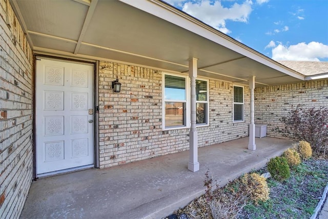 property entrance featuring covered porch and brick siding