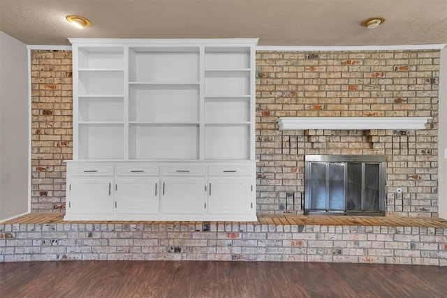 unfurnished living room with a brick fireplace and wood finished floors