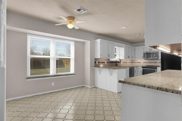 kitchen featuring stainless steel appliances, ceiling fan, visible vents, and light floors