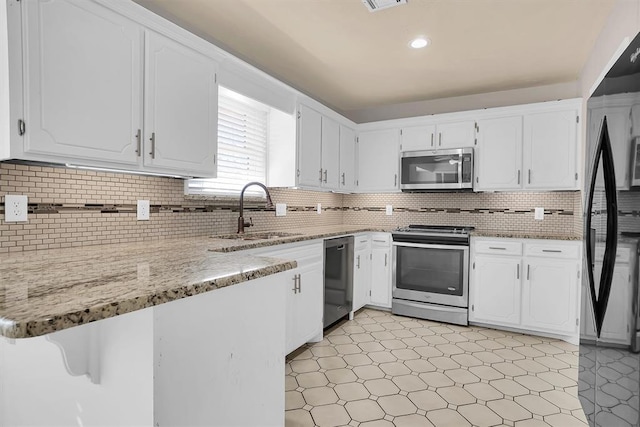 kitchen featuring a peninsula, light floors, white cabinetry, a sink, and appliances with stainless steel finishes